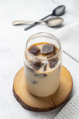 Iced latte with frozen espresso cubes, Iced coffe with milk on a white stone table