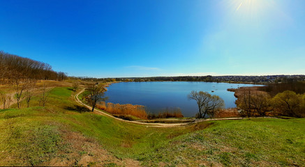

hilly shore with green grass dry reeds around the lake