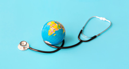 Stethoscope and world ball on pastel blue background with copy space for text. Save the wold and...
