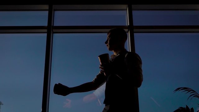 Strong slender man against the background of the pan-arm window. The bartender is coached to do tricks with shaker and ice.