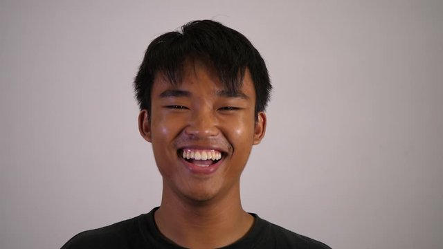 The asian boy smiles and looks happy with white background