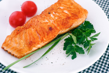 Salmon fillet with vegetable on white plate.