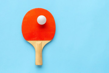 Red racket for table tennis with white ball on blue background. Ping pong sports equipment in...