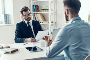 Two confident young men in formalwear communicating together whi
