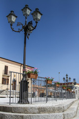 Fototapeta na wymiar Old street lamp and flowers with blue sky at a village in Sardinia, Italy