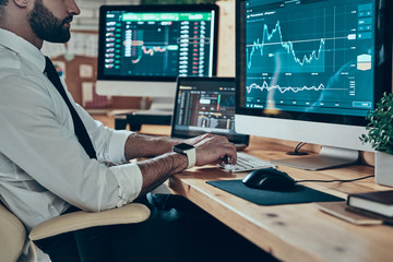 Close up of young modern man in formalwear working using compute