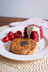 veggie burger  on plate with red rice and tomato