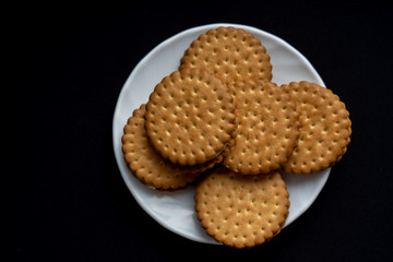 A bunch of cookies on white plate on dark black background