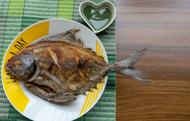 A fried fish with on dish and seafood sauce, Top view on on a wooden table with natural light, Food...