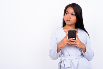 Portrait of young Asian woman thinking while using phone