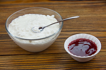 Tasty fresh grained cottage cheese on a plate on  wooden table