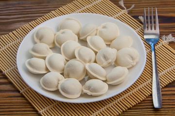 Raw frozen dumplings on  plate on table