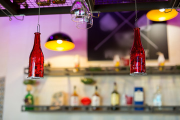 A bottle of red color hangs as a decoration in a bar or pub on the bar counter