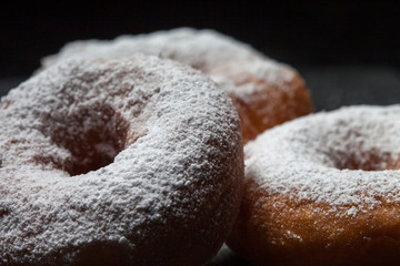 Fototapeta na wymiar Donuts with icing sugar on a black background