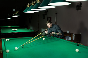 Man's hand and Cue arm playing snooker game or preparing aiming to shoot pool balls on a green...