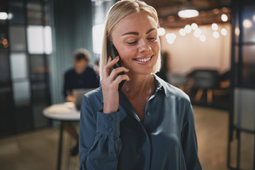 Smiling young businesswoman talking on her cellphone in an offic