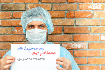man in a protective suit with the inscription on the sheet stay at home