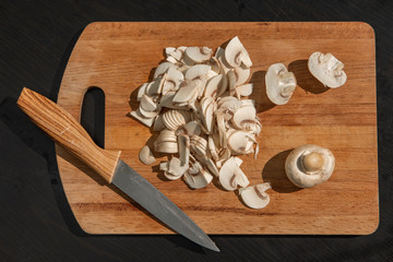 chopped champignons and knife on a wooden board