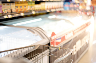 Blurred effect in the Supermarket aisle with empty silver  shopping trolley,