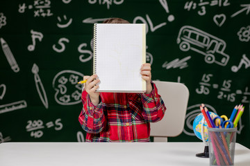 Cute child boy doing homework. Clever kid drawing at desk. Schoolboy. Elementary school student drawing at workplace. Kid enjoy learning. Home schooling. Back to school. Little boy at school lesson