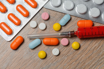 Concept of treatment options for COVID virus infection. Colorful syringes and tablets close-up.