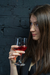 A beautiful, young woman is standing against a stone wall.