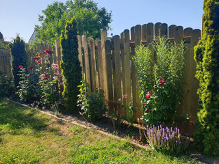 Gartenzaun aus Holz als Sichtschutz mit einer Blumenrabatte