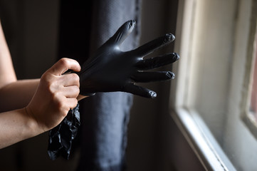 Indoors photo with unrecognizable person wearing black latex medical gloves in times of coronavirus...