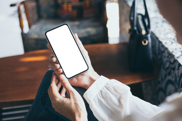 cell phone Mockup image blank white screen.woman hand holding texting using mobile on desk at coffee shop.background empty space for advertise text.people contact marketing business,technology