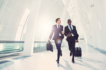 Two businessmen rushing along an airport departure hall