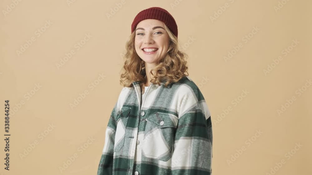 Sticker Happy pretty woman in knit hat and shirt posing and looking at the camera over beige background