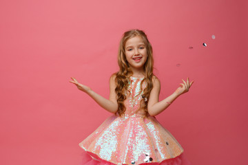 happy Little girl catches confetti on pink background, holiday concept