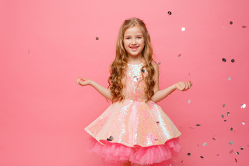 happy Little girl catches confetti on pink background, holiday concept