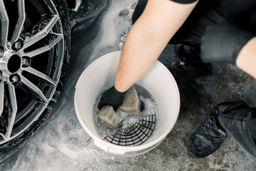 Car wash and detailing concept. Top view of washing tools in car wash service, white bucket with...