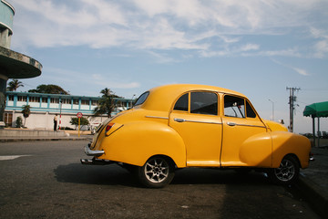 Small yellow car parked on streets of Havana