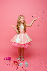 happy Little girl catches confetti on pink background, holiday concept