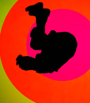 Young, attractive fit man, making a sideflip, showing his flexibility and skills. Oval and colorful texture in background 