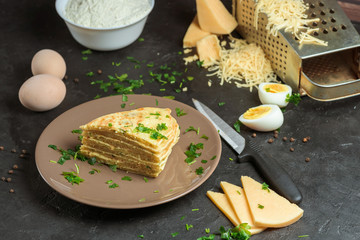 cheese tortilla with greens and cheese is cut into triangles on a dark background . ingredients grated cheese, eggs, gluten-free chickpea flour. vegetarian Breakfast. the view from the top