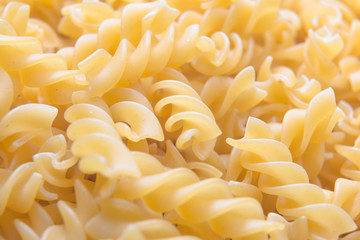 Fusilli. / A large quantity of pasta laid flat. the pasta is solid, long, thick, corkscrew or spiral shaped / Fusilli background
