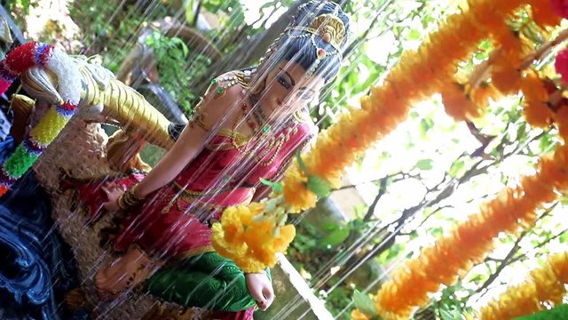 Phra Mae Thorani, goddess from Buddhist mythology, behind water of fountain. 