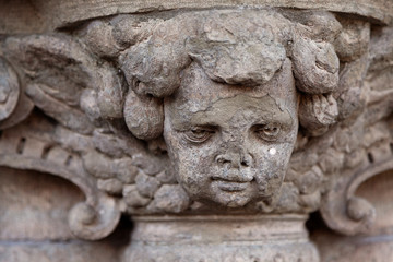 detail of old stone statue placed at door, almost looks like a cherub