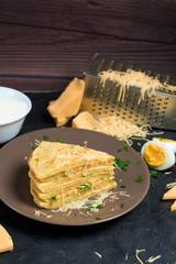 pancake with cheese, herbs and egg for Shrovetide. cheese tortilla is cut into pieces and sprinkled with cheese . on a dark background, the top view. space for text.