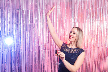 Party, drinks, holidays and celebration concept - smiling woman in evening dress with glass of sparkling wine over shiny background.