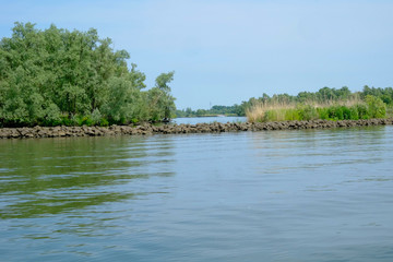 The long breakwater made up of rocks in the middle of idyllic blue lake