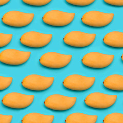 Flat lay Seamless Pattern made with ripe yellow mango fruit over blue background.