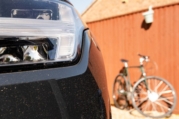 Shallow focus of the xenon headlights of a luxury SUV. The background shows a vintage bicycle seen...