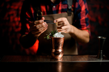 Fototapeta na wymiar Close-up Barman's hand decorates with spikelet metal glass using tweezers