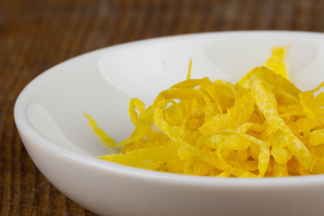 fresh lemon zests in a small white bowl closeup