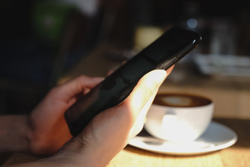 Blurred a woman holding a smart phone, side view at cafe.