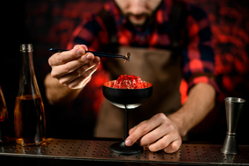 close-up. Bartender gently decorates glass by plant